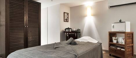 A bedroom with a bed, a wardrobe, a nightstand, and a shelf unit.