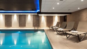 A modern indoor swimming pool with clear water, surrounded by lounge chairs and a ceiling with recessed lighting. - Radisson Blu Hotel, Edinburgh City Centre (Edinburgh)