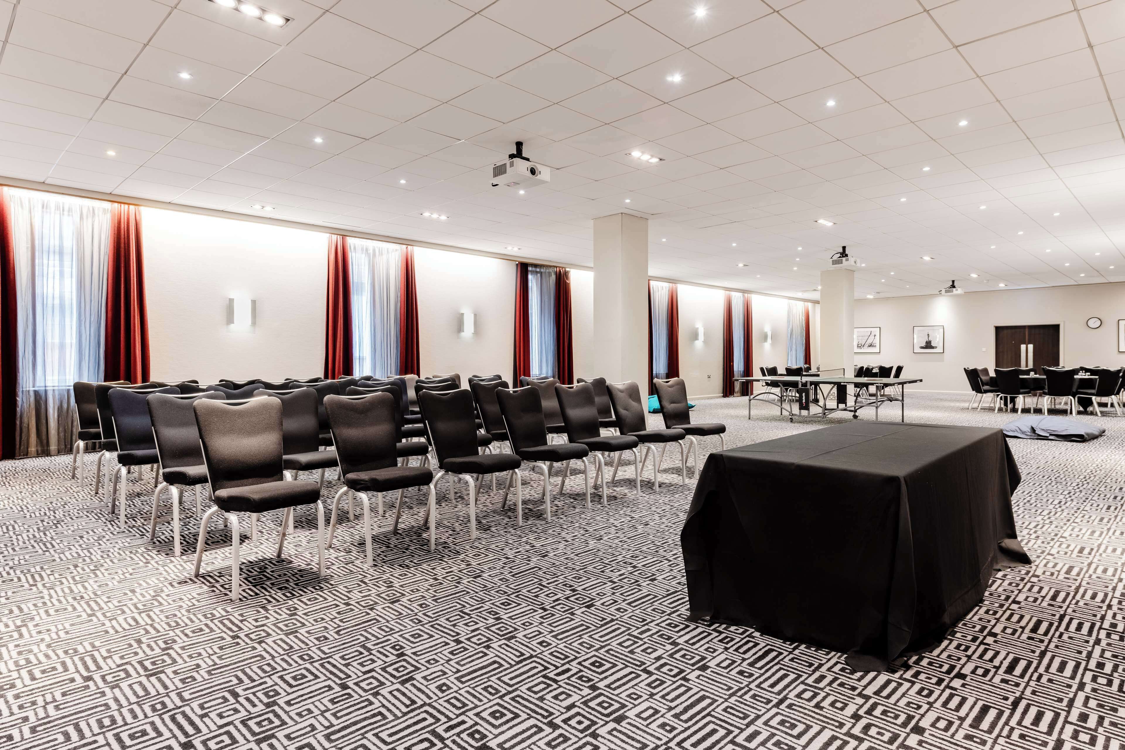 A conference room with rows of chairs, a projector, and a table with a black tablecloth.