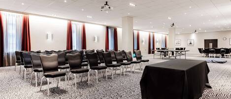 A conference room with rows of chairs, a projector, and a table with a black tablecloth.