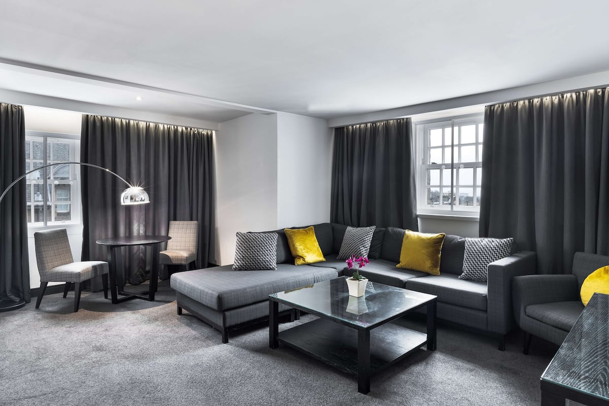 Un salon moderne avec un canapé gris, une table basse ronde et un lampadaire.