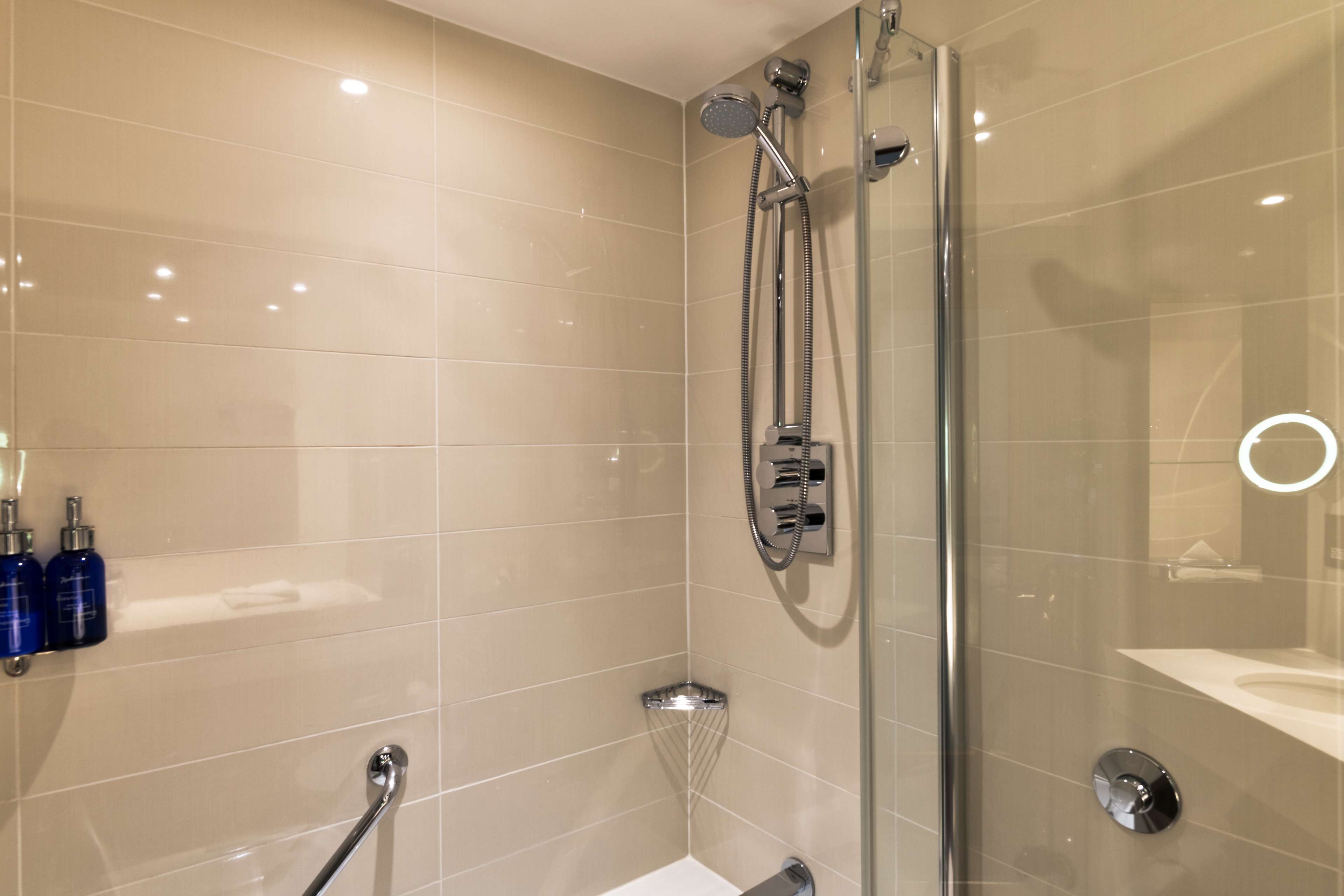A modern bathroom with a glass shower enclosure, a handheld showerhead, and a handheld shower attachment.