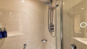 A modern bathroom with a glass shower enclosure, a handheld showerhead, and a handheld shower attachment.