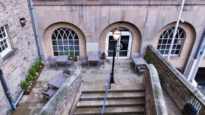 A courtyard with stone steps leading to a door, surrounded by arched windows and outdoor seating. - Radisson Blu Hotel, Edinburgh City Centre (Edinburgh)