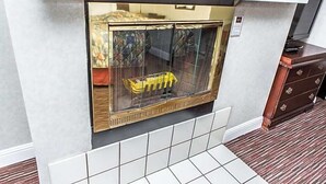 A room with a built-in fireplace, a wooden cabinet, and a tiled floor. - Rodeway Inn & Suites (Denver)