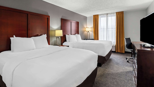 Une chambre d’hôtel avec deux lits, un bureau, une chaise et un téléviseur.