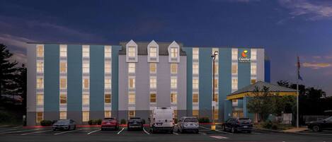 A hotel with a parking lot and several cars parked in front.