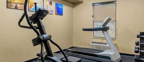 A gym with an elliptical machine, a treadmill, and a set of dumbbells.