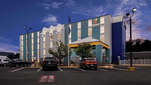 Un hôtel Comfort Inn & Suites doté d’un parking, d’un mât avec un drapeau et offrant une vue sur un ciel dégagé.