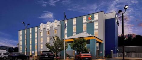 Un hôtel Comfort Inn & Suites doté d’un parking, d’un mât avec un drapeau et offrant une vue sur un ciel dégagé.