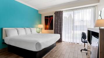 Une chambre d’hôtel avec un lit, un bureau, une chaise et des rideaux.