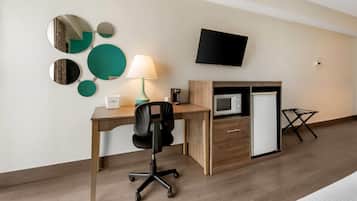 Habitación de hotel con escritorio, silla, televisor, microondas y refrigerador.