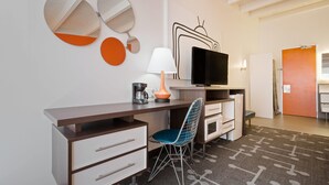 A modern hotel room with a desk, chair, television, and decorative mirrors.