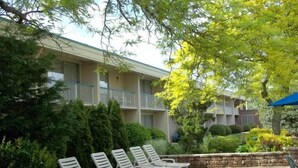 A courtyard with a row of white lounge chairs, a stone wall, and a building with balconies.