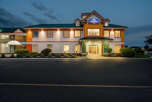 Un hotel Howard Johnson con una estructura de dos pisos, una entrada cubierta y una fachada bien iluminada.