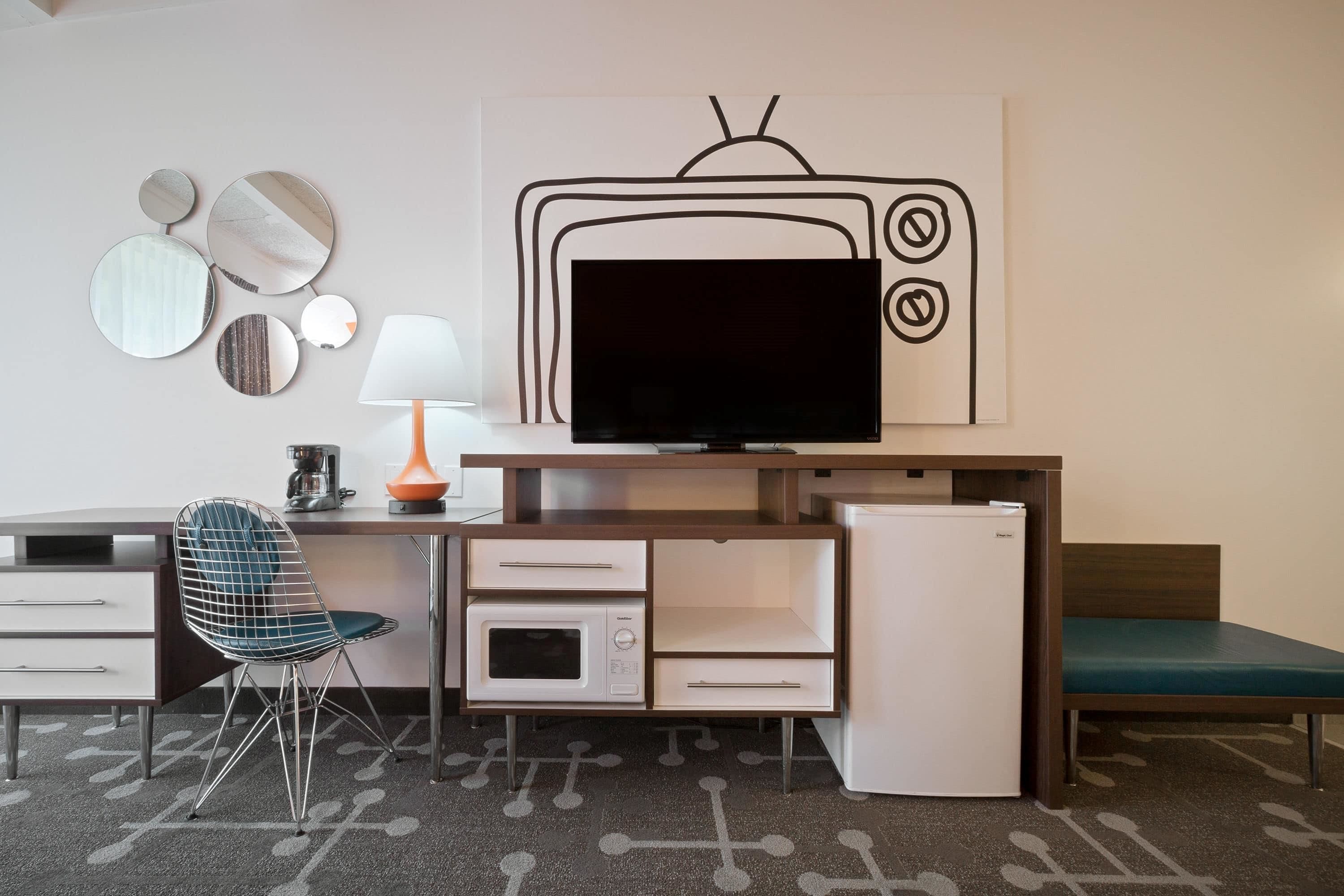Pieni huone, jossa on sänky, työpöytä, jossa on litteänäyttöinen televisio, mikroaaltouuni ja jääkaappi.