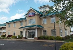 Un hotel con un letrero que dice "Hotel Johnson", que presenta una estructura de dos pisos con techo verde y entrada cubierta.