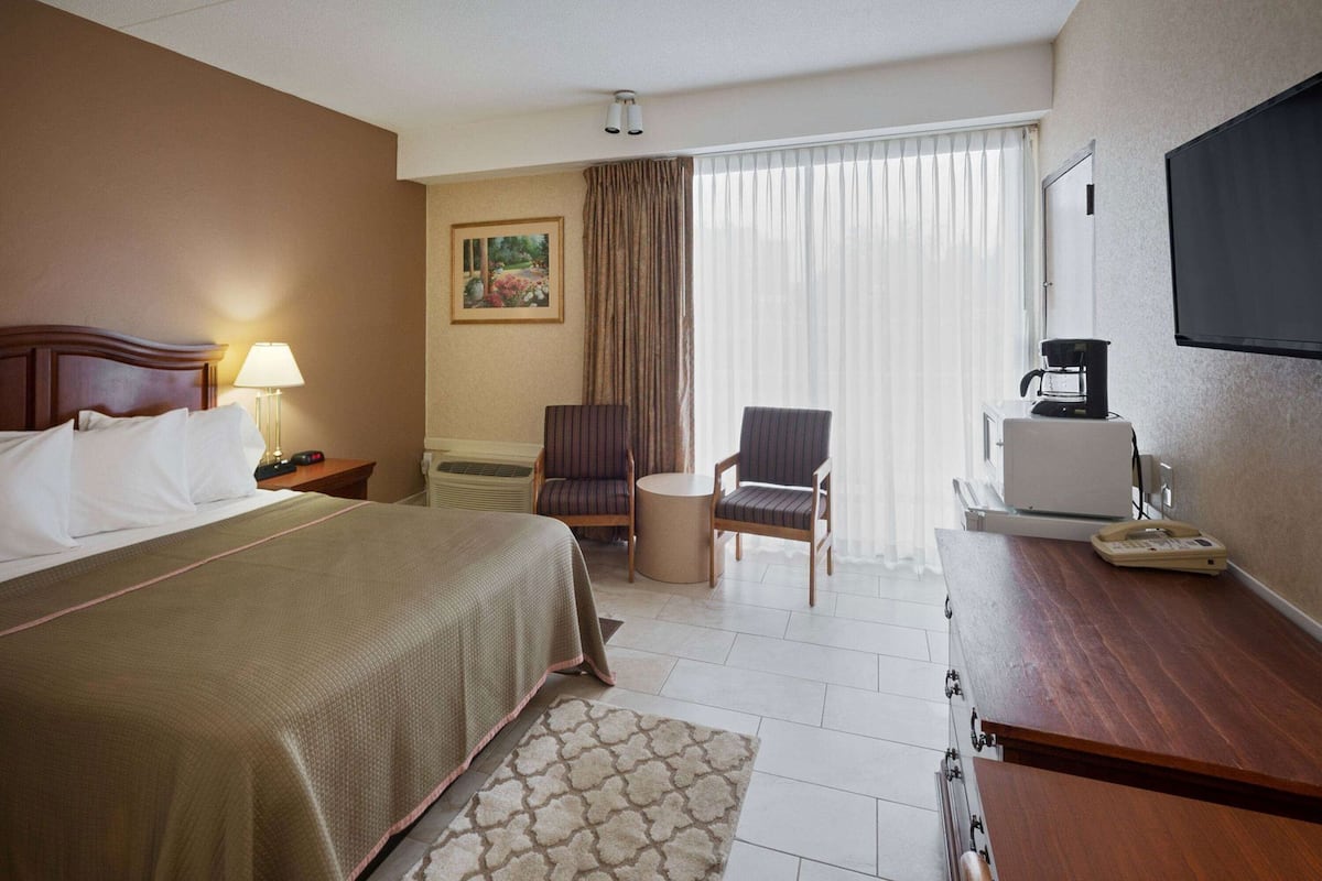 Une chambre d’hôtel équipée d’un lit, d’un bureau, d’une chaise, d’une machine à café et d’un téléviseur.