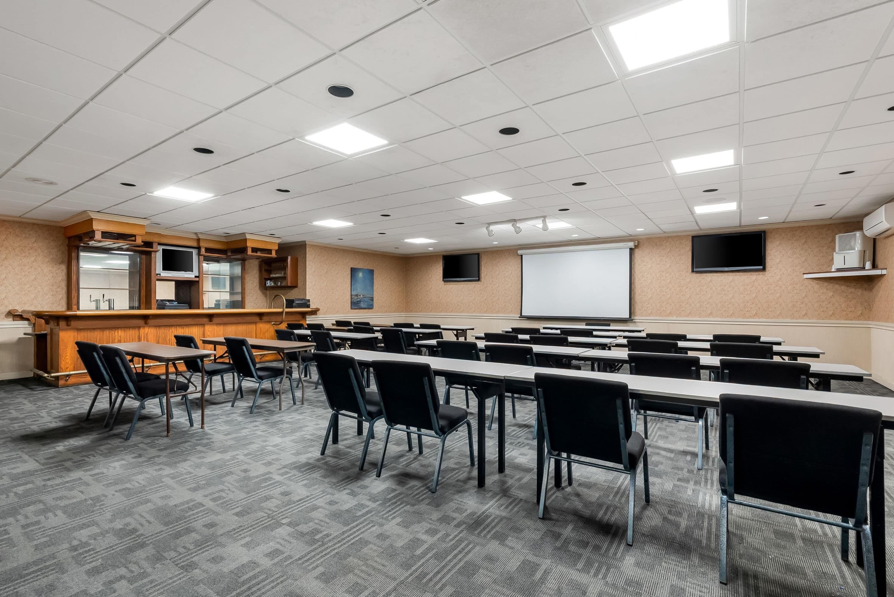 A conference room with a long table, chairs, a podium, and a projection screen.