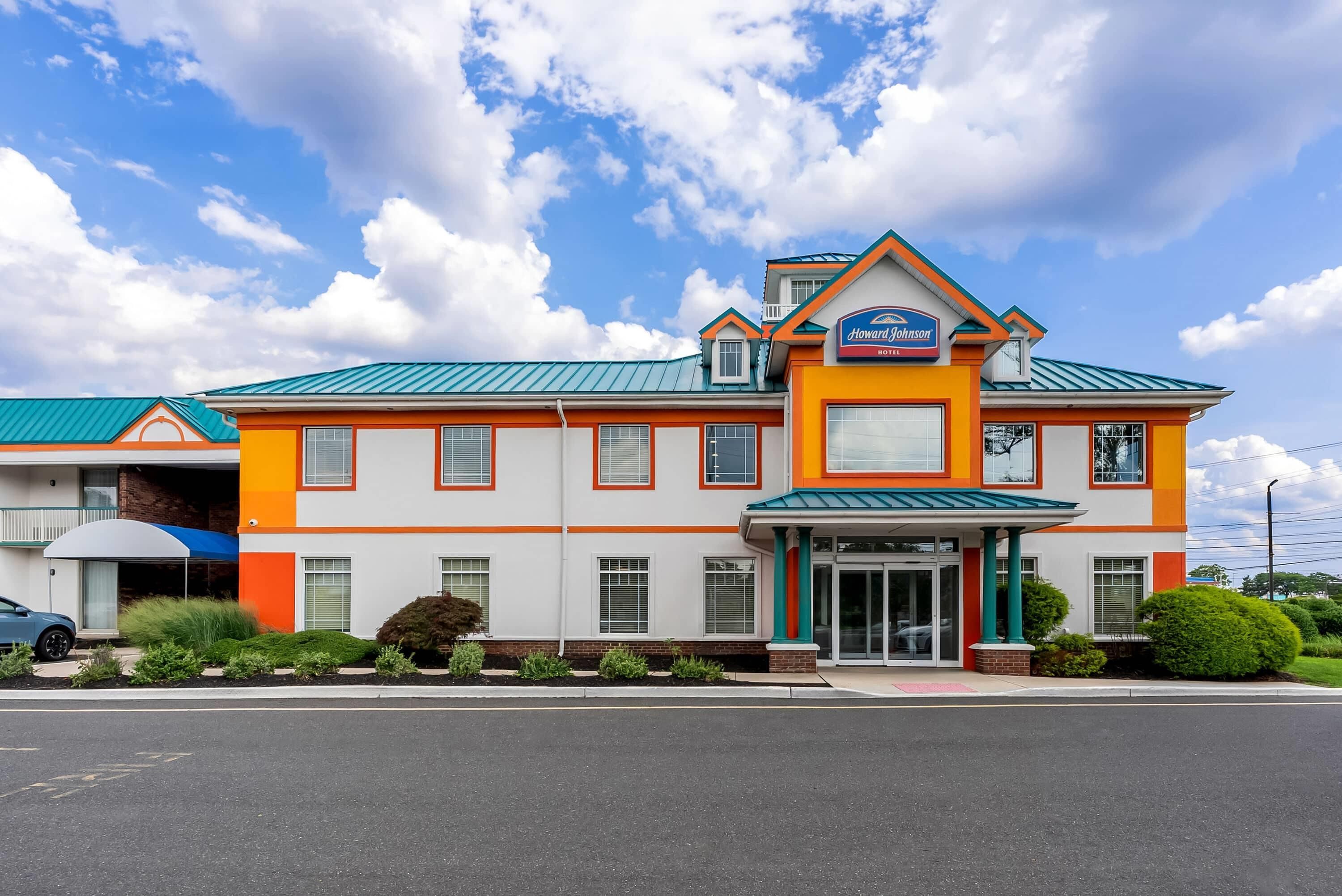 Un hotel Howard Johnson con diseño moderno, que cuenta con una entrada destacada y un estacionamiento al frente.