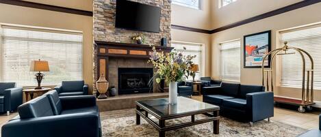 A spacious lobby with a fireplace, comfortable seating, and a flat-screen TV mounted on the wall.