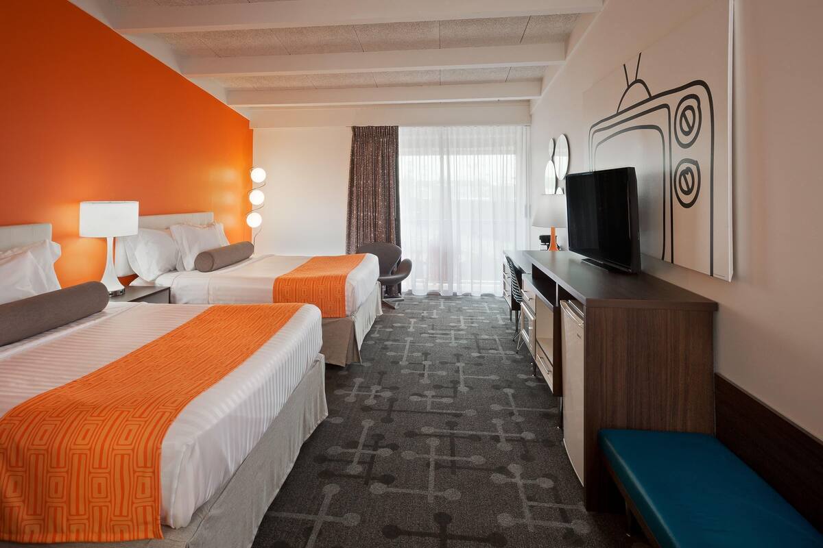 Une chambre d’hôtel avec deux lits, une télévision, un bureau et un banc.
