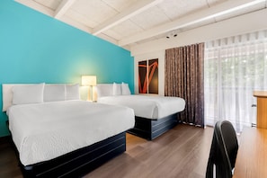 A hotel room with two beds, a desk, a chair, a lamp, and a large window with curtains. - Howard Johnson Hotel by Wyndham Toms River (Toms River)