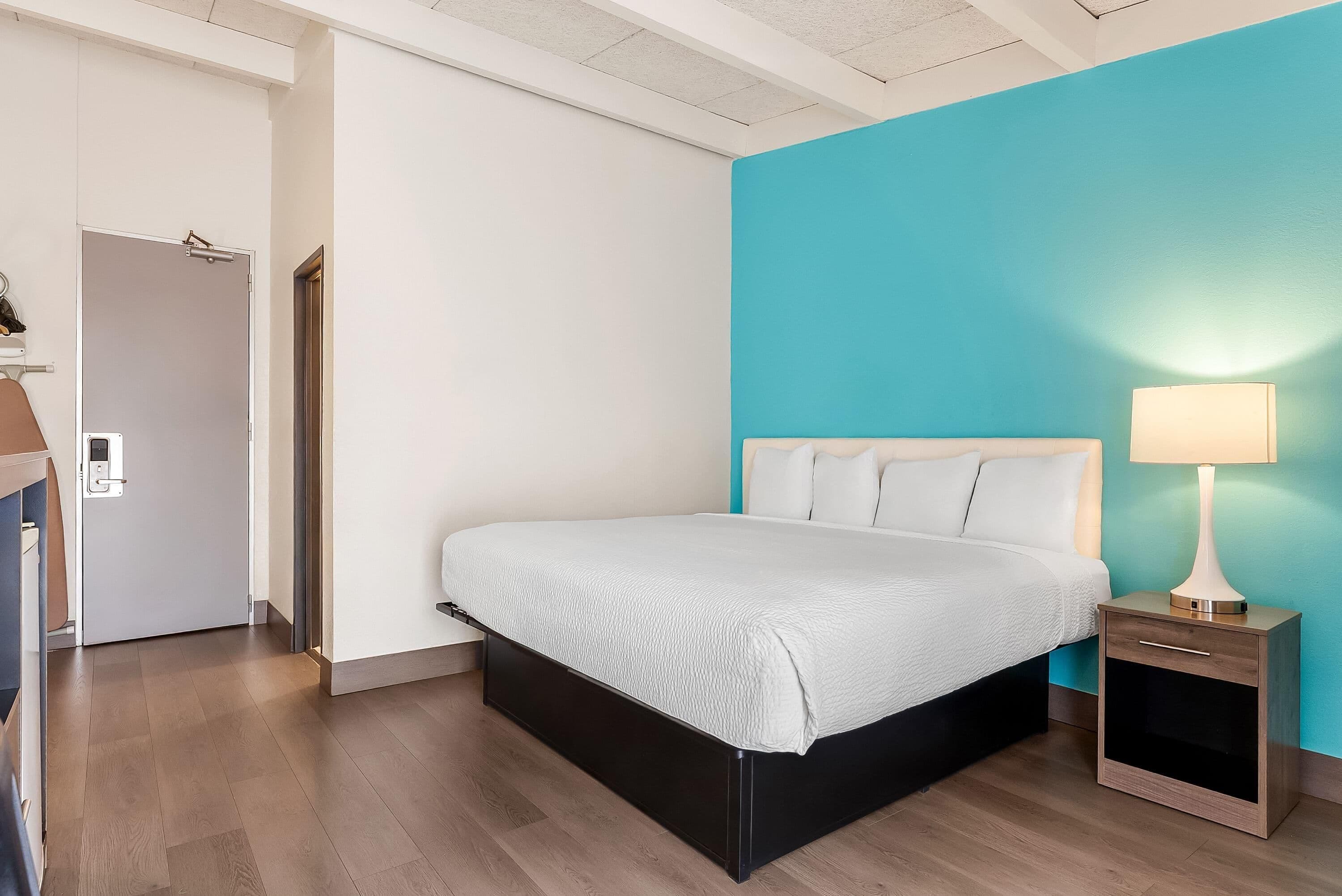 Una habitación de hotel con cama, mesita de noche y lámpara.