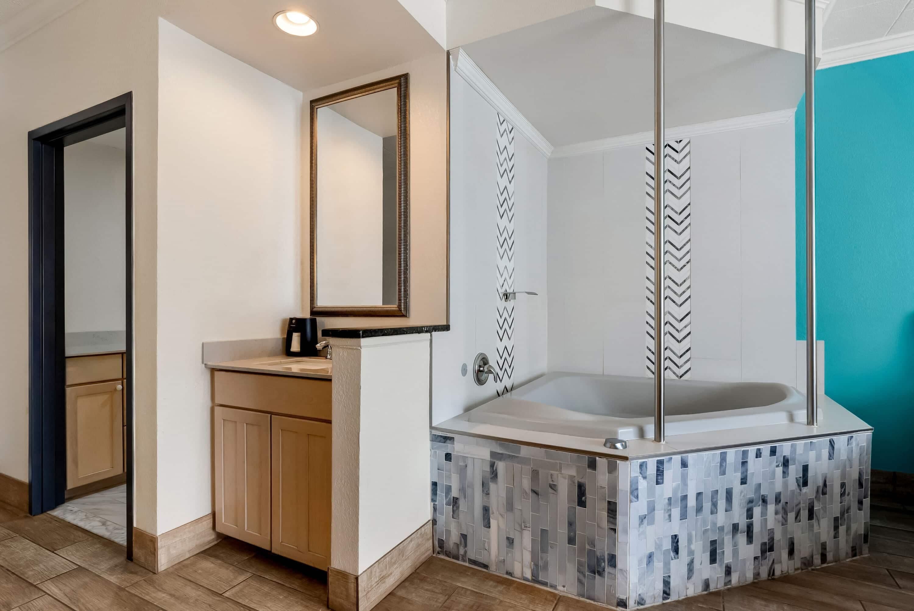 A modern bathroom with a freestanding bathtub, a large mirror, and a herringbone-patterned shower enclosure.