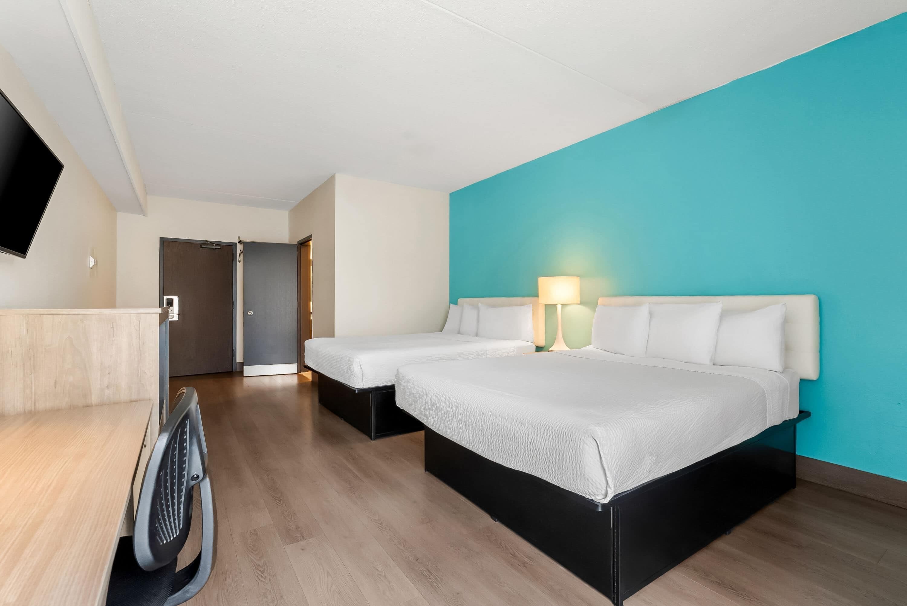Una habitación de hotel con dos camas, un escritorio y un televisor.
