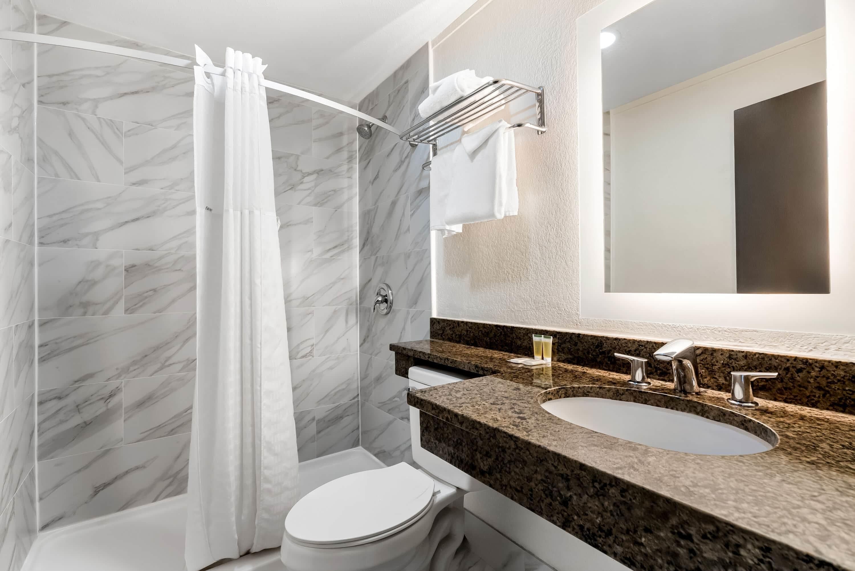 A modern bathroom with a shower, toilet, and sink.