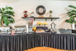 A buffet setup with food items, a clock, and decorative elements on a wall.