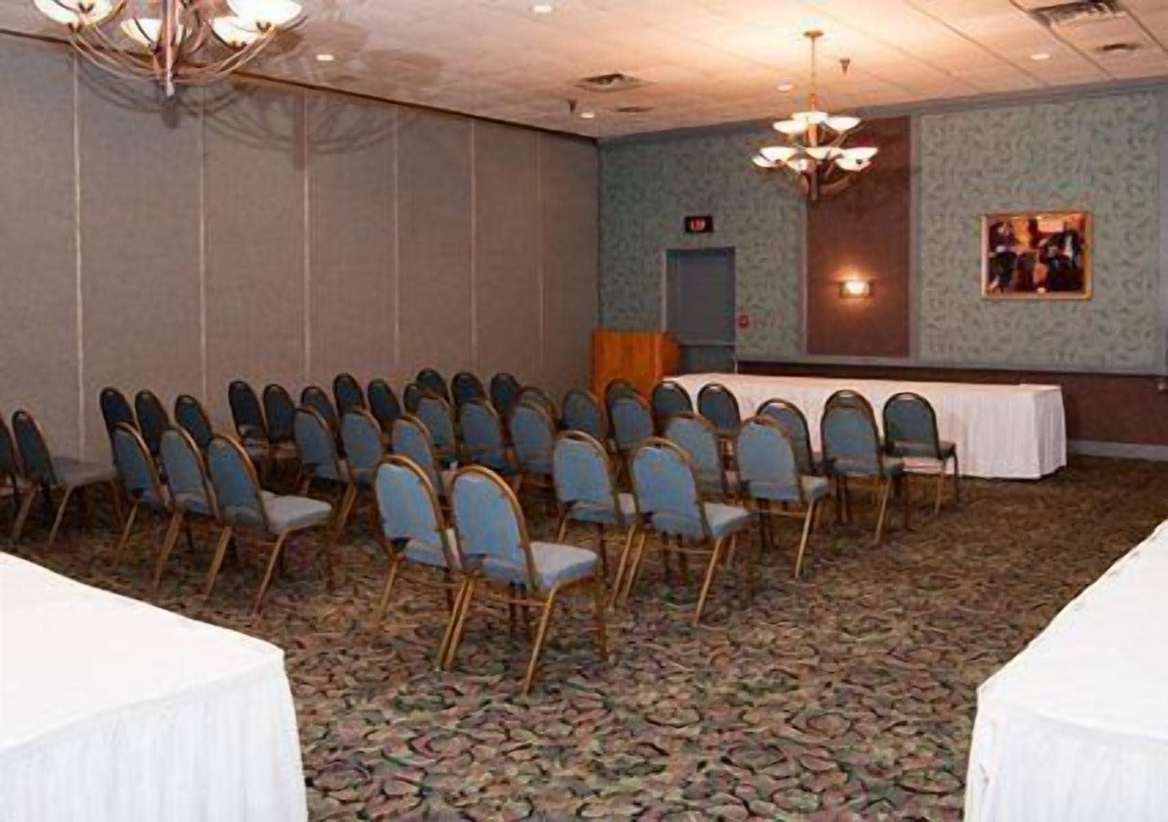 A conference room with rows of chairs, a table with a white tablecloth, and a chandelier.