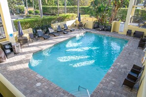 Una piscina al aire libre, sombrillas, sillones reclinables de piscina