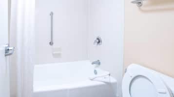 A bathroom with a white bathtub, a toilet, and a shower curtain.