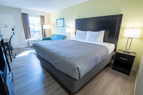 Une chambre d’hôtel avec un grand lit, un bureau, une chaise et une table de chevet avec des lampes.