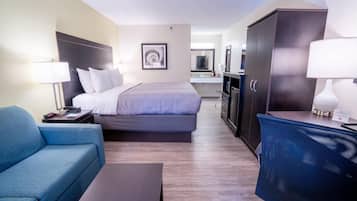 Habitación de hotel con cama, escritorio, silla, televisor y armario.