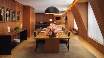 A modern dining area with a wooden table set for six, surrounded by chairs, and a central floral arrangement.