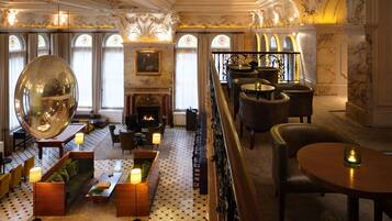 Eine luxuriöse Lobby mit Kamin, Sitzbereichen und einem großen Spiegel.