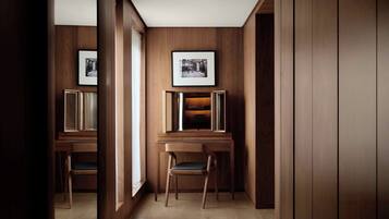 A hallway with wooden paneling, framed pictures on the walls, and a desk with a chair.