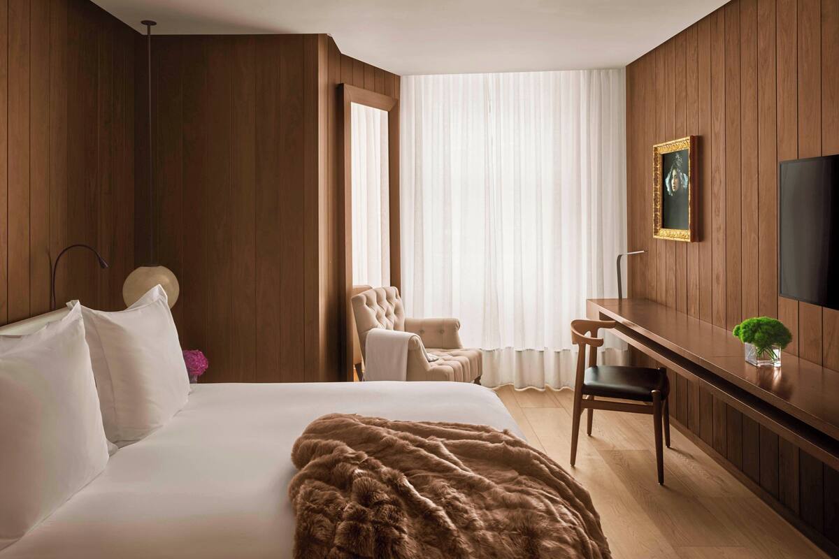 Habitación de hotel con una cama grande, un escritorio, una silla y una televisión.