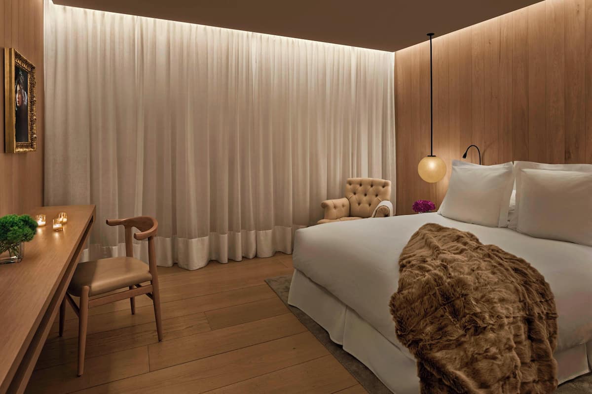 Un dormitorio moderno con una cama grande, un escritorio de madera y una silla.