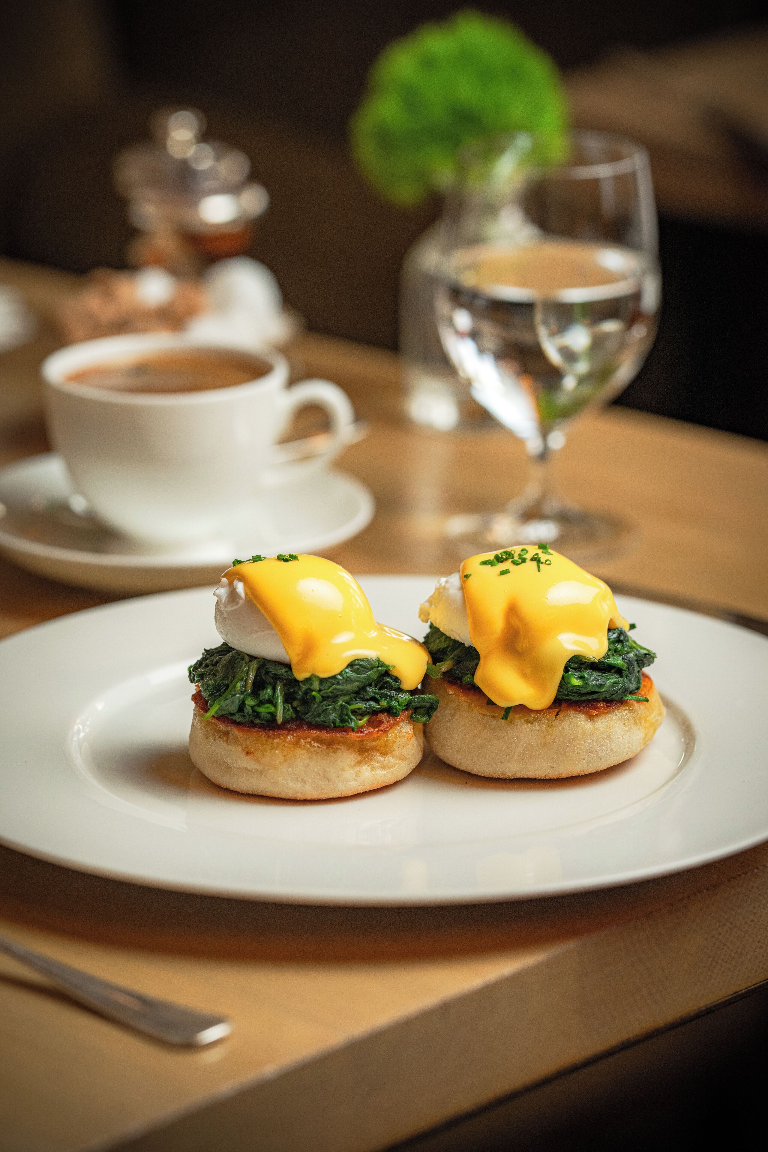 A plate with two eggs benedict sandwiches on a white plate.