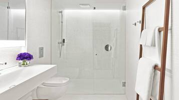 A modern bathroom with a glass-enclosed shower, a white sink, and a toilet.