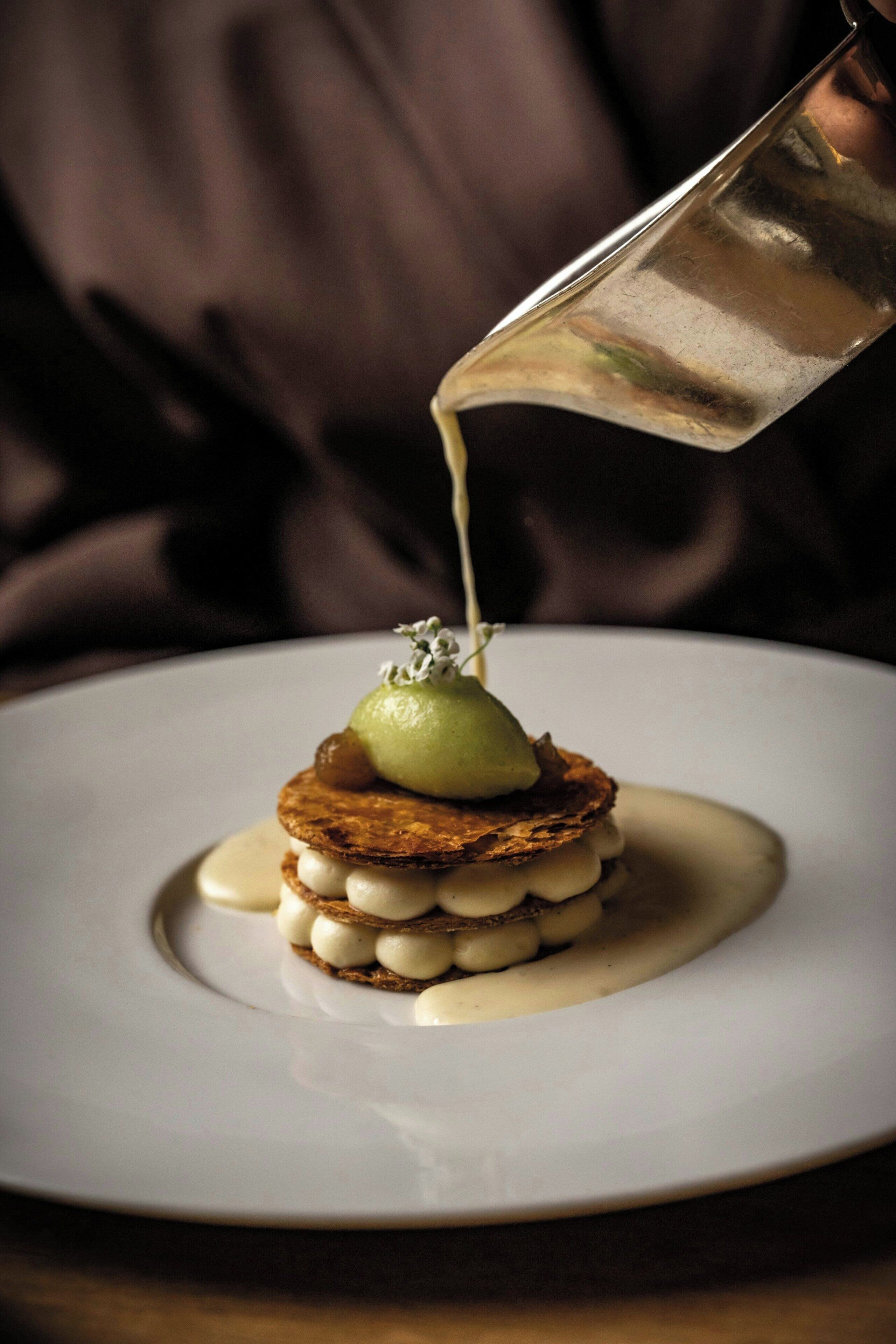 A dessert on a white plate with a pouring sauce.