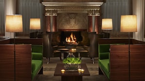 A luxurious lobby with a grand fireplace, elegant green sofas, and classic decor. - The London EDITION (London)