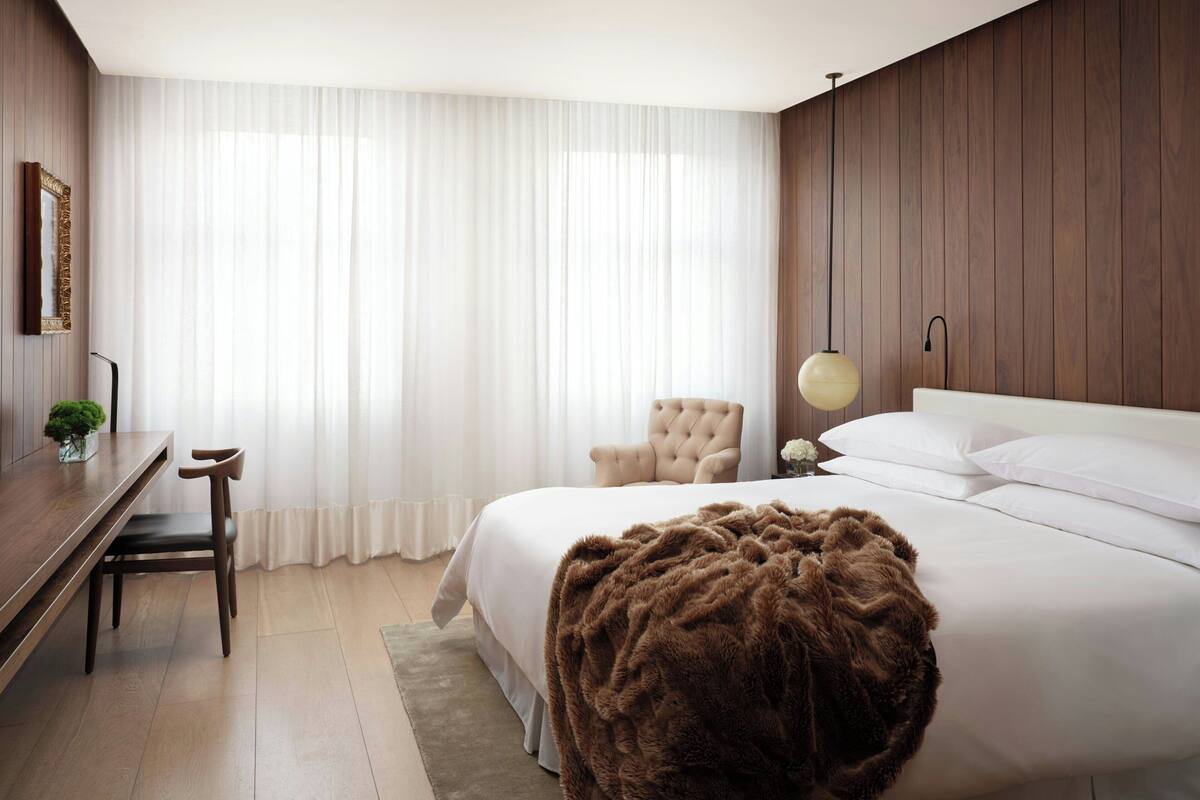 Una habitación de hotel moderna con una cama grande, un escritorio y una silla.