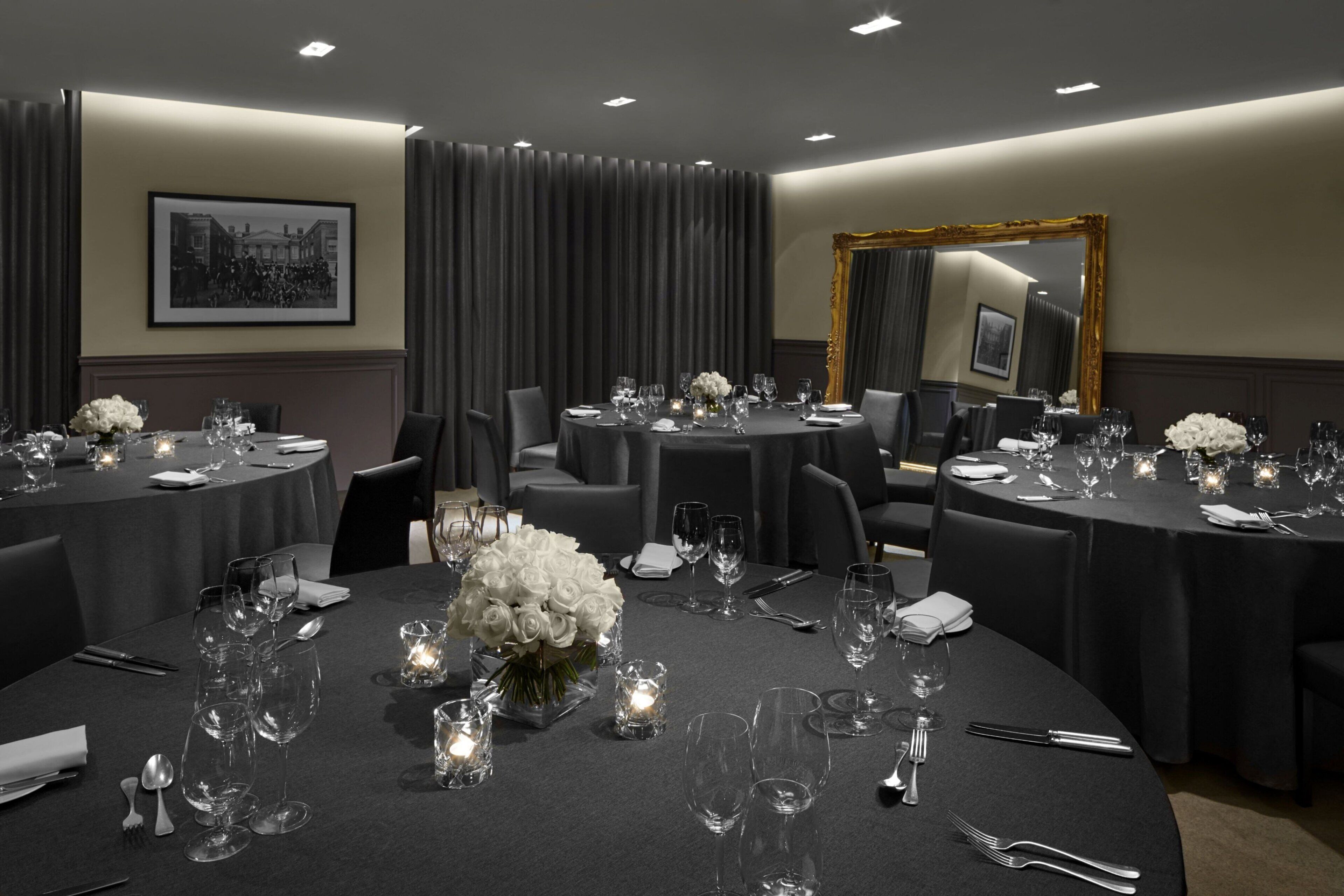 A conference room with round tables, chairs, and floral centerpieces.