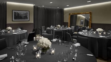 A conference room with round tables, chairs, and floral centerpieces.