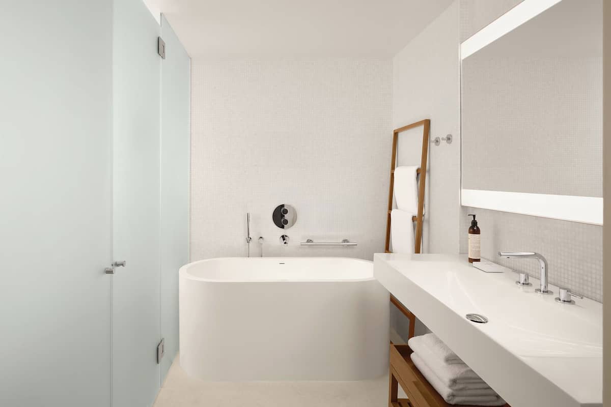 A modern bathroom with a freestanding bathtub, a large mirror, and a vanity with a sink.